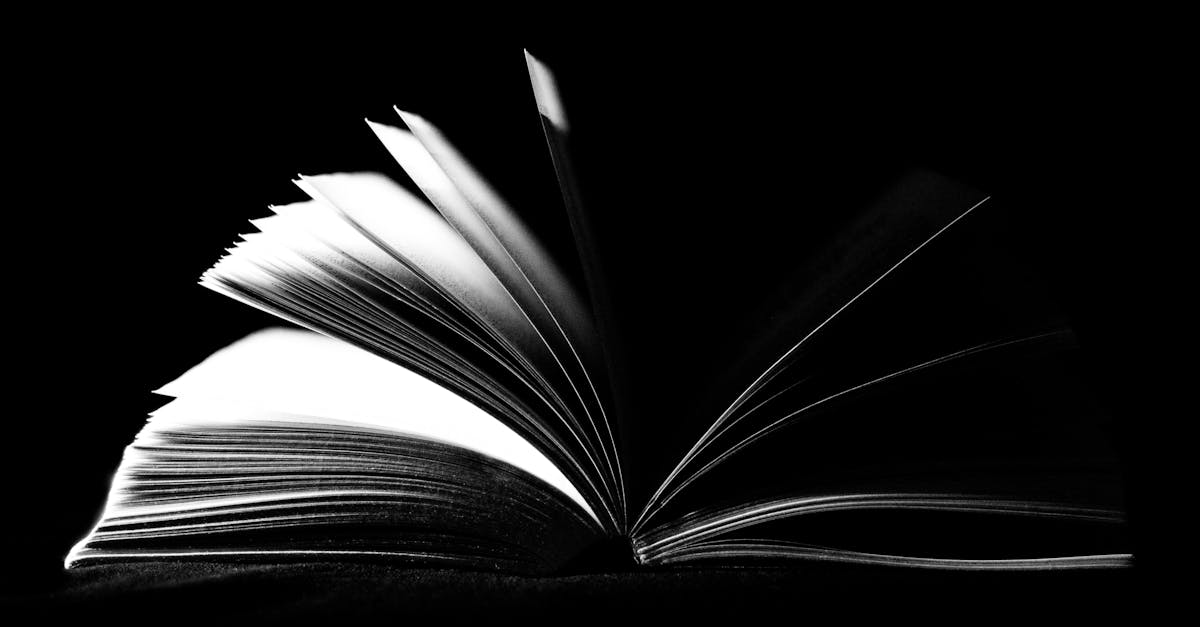 A striking black and white image of an open book with pages fanned out against a dark background.