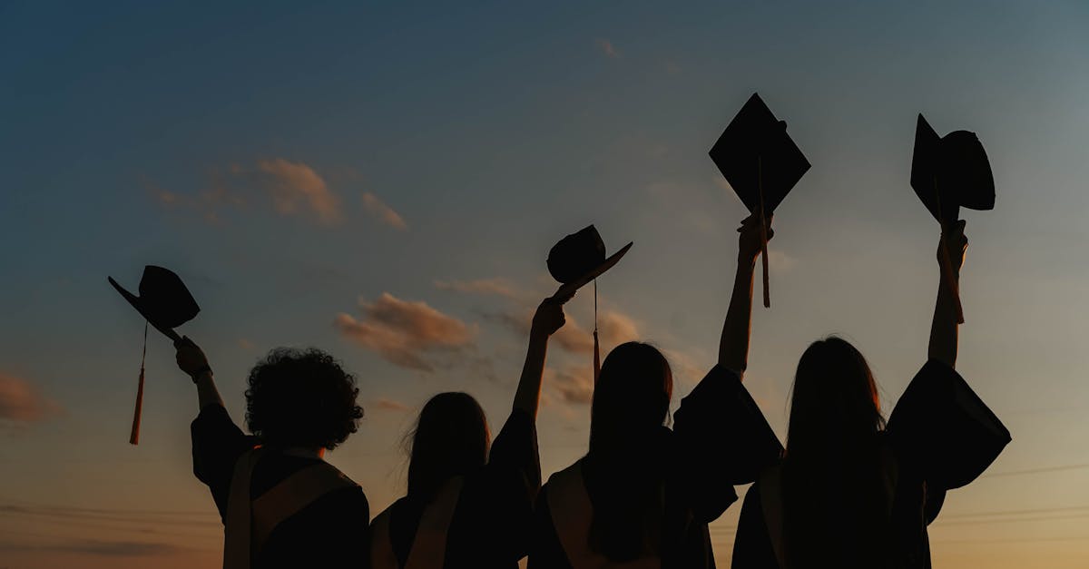 Silhouette of graduates raising caps in joy at sunset.