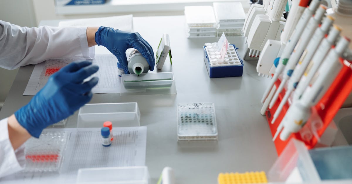 Scientist in blue gloves handling lab equipment and samples.
