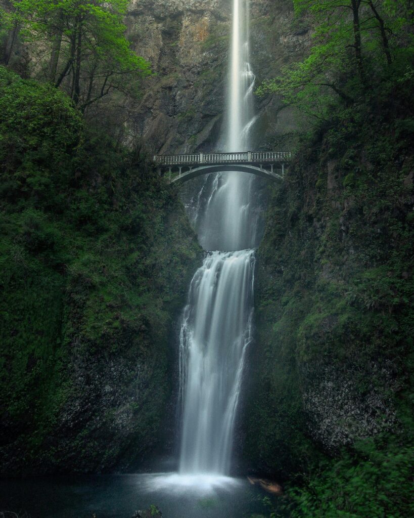 Stunning view of a cascading waterfall with a bridge in Oregon, perfect for nature enthusiasts.
